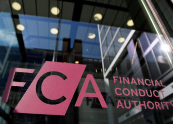 Glass door with the Financial Conduct Authority logo in pink. The building's interior reflects in the glass, showing a row of lights and a high ceiling. | FintechZoom
