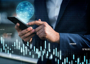 A person in a suit uses a smartphone, seamlessly navigating the US fintech market. A futuristic holographic globe and financial chart graphics overlay the scene, highlighting advanced technology and data analysis. | FintechZoom