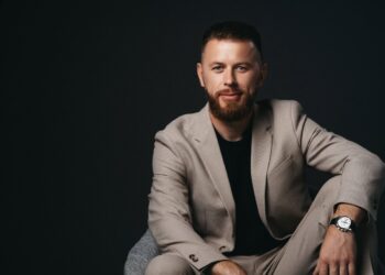 Igor Zotko. He is against a dark background, with a relaxed posture and a slight smile. He wears a wristwatch on his left wrist. | FintechZoom