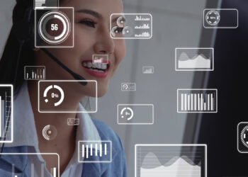 A woman wearing a headset is smiling while looking at a computer screen in a dentist's office. Transparent digital data graphics, including charts and graphs, overlay in the foreground, hinting at data analysis or customer support. | FintechZoom