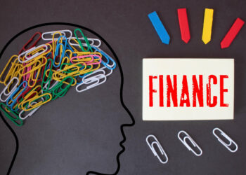 Silhouette of a head filled with colorful paperclips, symbolizing thoughts directed toward making smarter financial decisions. A white card with "FINANCE" in red letters is to the right, surrounded by more paperclips and red, blue, and yellow arrow markers on a black background. | FintechZoom