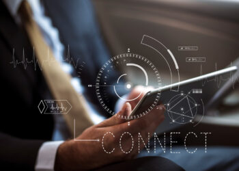 A person sitting in a car, dressed in a suit, holds a tablet. Overlay graphics show futuristic interface elements like a compass and heartbeat lines, with the words "CONNECT" and "Leverage APIs" prominently displayed. | FintechZoom