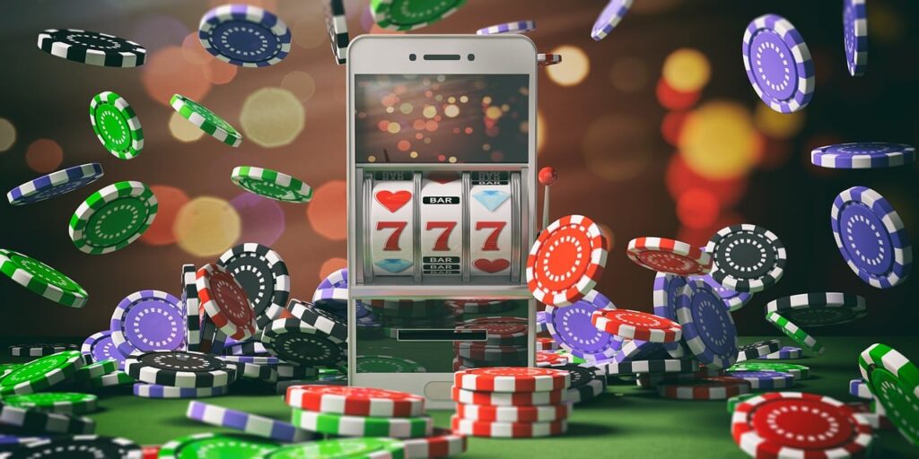 Smartphone displaying a slot machine with triple sevens amid a cascade of colorful poker chips on a green surface and blurred lights in the background.