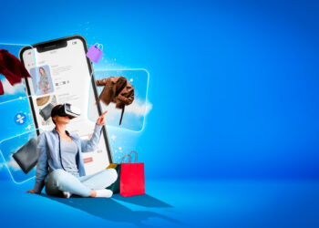 A person wearing a VR headset sits on a blue floor, interacting with virtual clothing items like jackets and handbags. A giant smartphone screen displays a shopping app, with colorful shopping bags nearby. The background is a vibrant blue. | FintechZoom
