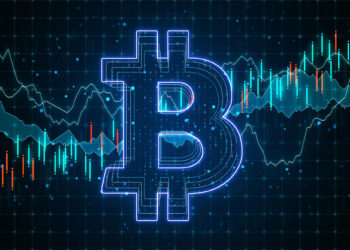A glowing blue Bitcoin symbol is centered over a background featuring a digital chart with fluctuating lines and candlestick patterns. The chart represents financial or cryptocurrency market trends. | FintechZoom