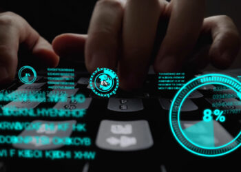 Hands typing on a keyboard with digital blue holographic displays, showing a pie chart at 8%, binary code, and circular icons. The futuristic overlay suggests data analysis or hacking. | FintechZoom