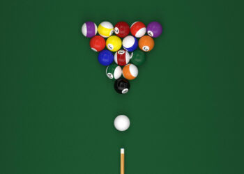 Aerial view of a billiards table with a triangle formation of colorful balls set for break. A cue ball sits ready to be struck by a cue stick positioned straight on the green felt surface. | FintechZoom