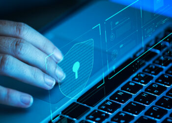 A person taps a holographic lock icon hovering above a laptop keyboard, symbolizing privacy and data protection. The image conveys a sense of futuristic digital security. | FintechZoom