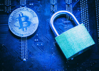 A Bitcoin coin and a green padlock rest on a blue circuit board, symbolizing cryptocurrency security, digital protection, and the importance of crypto wallets for secure online transactions. | FintechZoom