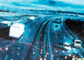 A digitally enhanced image of trucks and cars driving on a highway, overlaid with a network of red and blue lines and dots, representing data connectivity or smart transportation technology. | FintechZoom