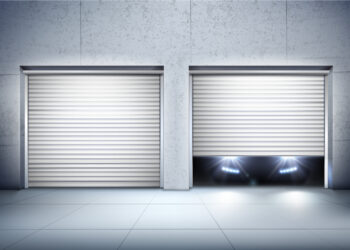 Two white roll-up garage doors on a modern building; one door is fully closed, while the other is partially open with headlights from a car shining out from behind it. | FintechZoom