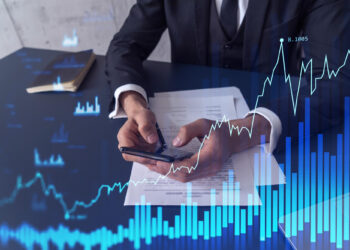 A person in a suit uses a smartphone at a desk with documents, notebook, and pen, overlaid with digital graphics of rising charts and bar graphs, symbolizing business growth and opportunities in Pre-IPO Companies. | FintechZoom