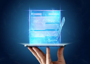 A hand holds a smartphone projecting a glowing, holographic digital document with text, a pen, and a signature field, all set against a dark blue background. | FintechZoom