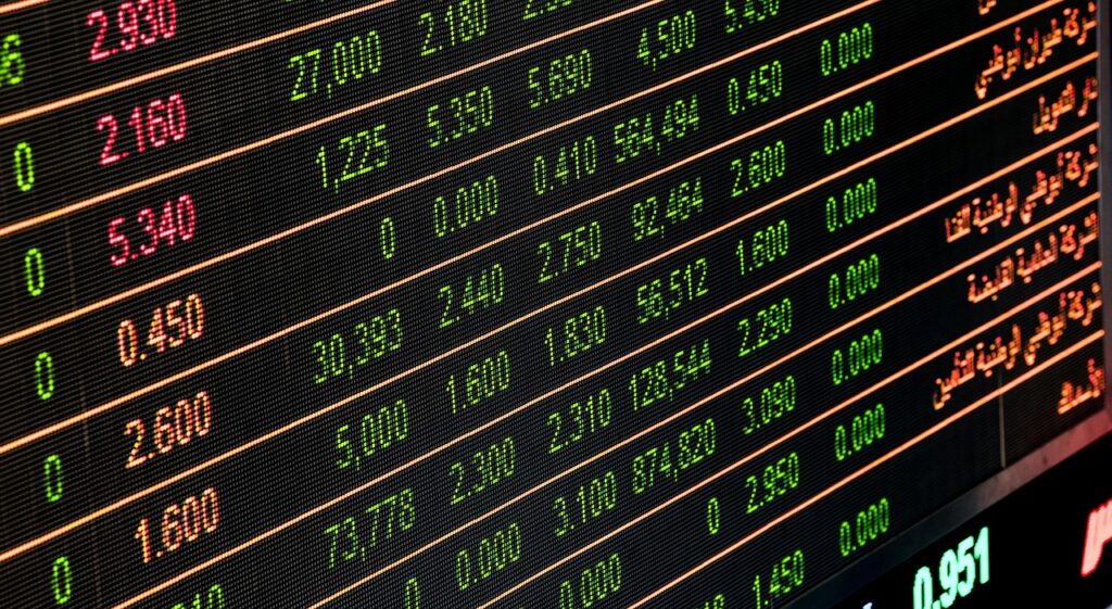 Close-up of an electronic stock market display showing rows of numbers and prices in green and red, with some text in Arabic on the right side—perfect for those interested in Trading Forex. | FintechZoom
