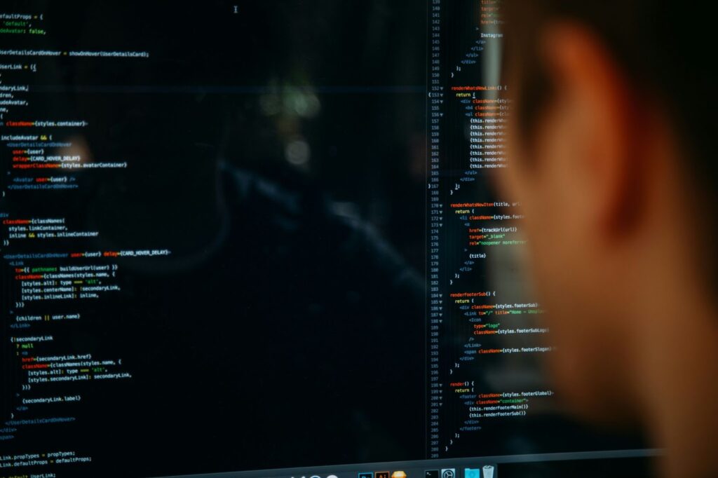 A person is looking at a computer screen displaying lines of code in a text editor, with colored syntax highlighting on a dark background—perhaps building the next Buy Now Pay Later feature. The person’s face is partially out of focus. | FintechZoom