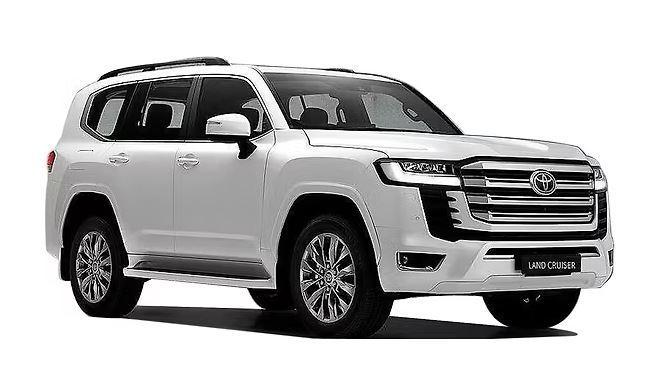 A white Toyota Land Cruiser SUV is parked, viewed from the front passenger side, highlighting its large SUV body, bold grille, and modern design. | FintechZoom