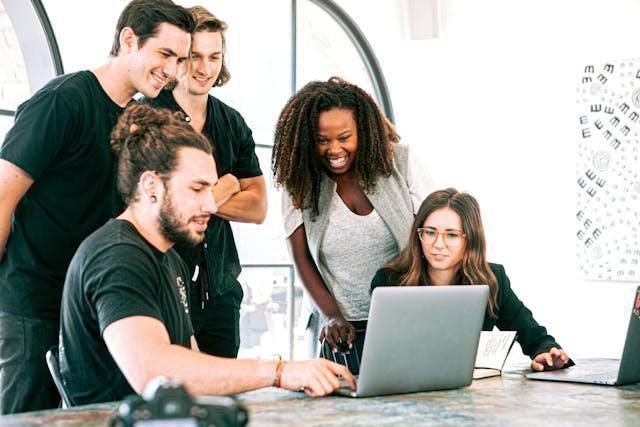 A diverse startup team gathered around a laptop.