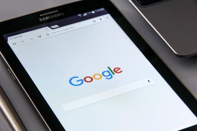 A Samsung tablet displaying the Google search homepage on its screen, placed next to a laptop on a desk—an ideal setup for tackling SEO challenges. | FintechZoom