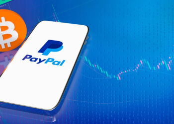 A smartphone displays the PayPal logo on its screen, next to a large orange Bitcoin symbol, set against a blue digital background with financial graph lines. | FintechZoom