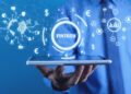 A person in a suit holds a tablet with digital graphics above it, including the word "Fintech," currency symbols, charts, and a globe, representing financial technology and global finance. | FintechZoom