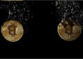 Two gold-colored Bitcoin coins are partially submerged in dark water, with bubbles and ripples around them against a black background. | FintechZoom