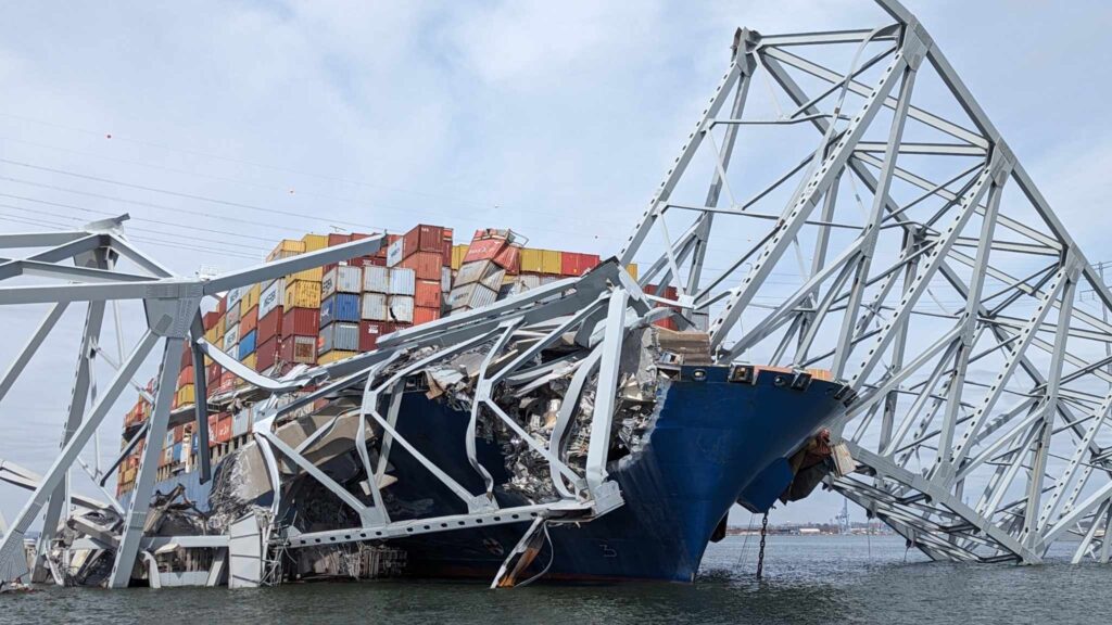 The container ship Dali crashed into a pylon of Baltimore’s Francis Scott Key Bridge, causing the entire bridge to collapse onto the water and resulting in significant damage to both the vessel and the bridge structure. | FintechZoom