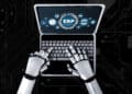 A robot with metallic hands types on a laptop keyboard displaying an ERP (Enterprise Resource Planning) interface and various business icons, set against a dark, tech-themed background. | FintechZoom
