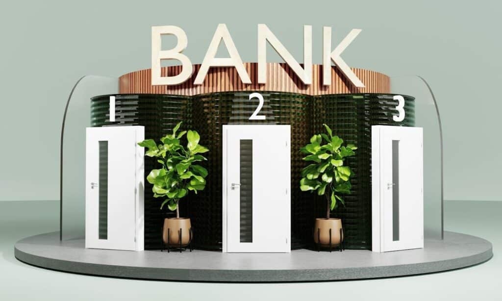 Three white doors labeled 1, 2, and 3 stand in front of large green plants and a dark, textured wall. Above them, large letters spell out "BANK." The scene is clean and modern. | FintechZoom