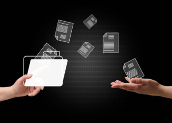 Two hands exchange digital files, represented by floating document icons, against a black background, symbolizing file sharing or data transfer. | FintechZoom