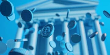 Blue-toned image showing digital coins with the Bitcoin symbol falling in front of a classical bank building with columns, representing cryptocurrency and financial institutions. | FintechZoom