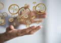 A person’s outstretched hands with floating golden percentage symbols between them, symbolising concepts like interest rates, finance, or discounts. The background is blurred, keeping focus on the symbols. | FintechZoom