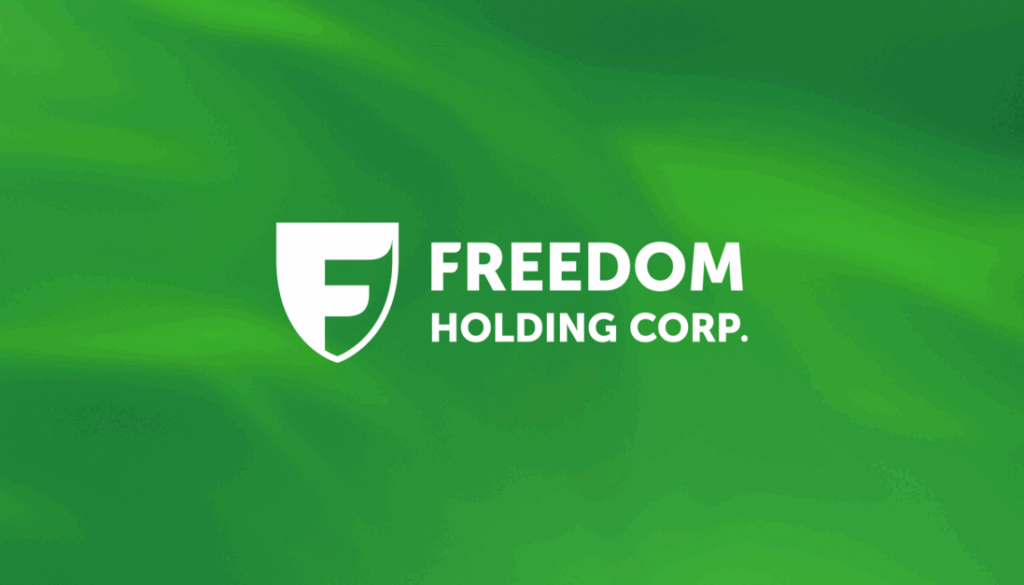 White Freedom Holding Corp. logo with a shield containing an “F” on a green gradient background. The company name is written in bold white text to the right of the shield. | FintechZoom