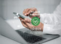 A person uses a smartphone and laptop, with a virtual screen displaying a green tick and the words “Payment Successful.” Icons for shopping and security appear around the screen. | FintechZoom