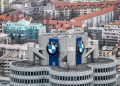Aerial view of BMW headquarters in Munich, Germany, featuring the iconic BMW logo on the cylindrical building, surrounded by residential and commercial buildings. | FintechZoom