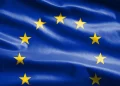 The European Union flag with twelve yellow stars in a circle on a blue background, representing unity among European countries. | FintechZoom