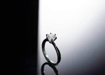 A solitaire diamond engagement ring with a dark band set against a contrasting black and white background. | FintechZoom
